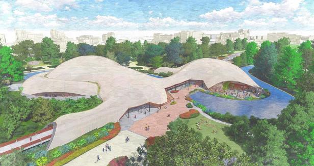 Eine Luftaufnahme der Multihalle Mannheim, umgeben von Grünflächen und einem Fluss.