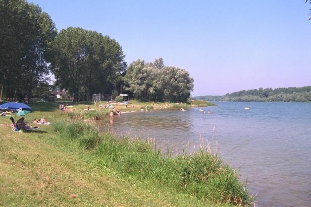 An einem sonnigen Tag entspannen sich Menschen an einem See.