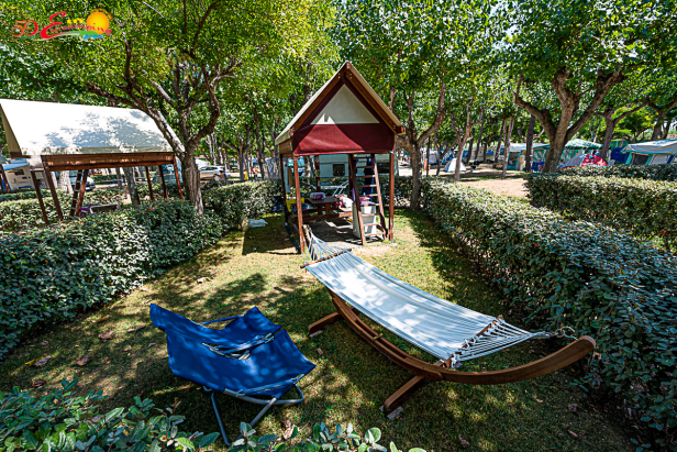 Eine Hängematte und ein blauer Stuhl stehen auf einem Campingplatz in Eurcamping Roseto.