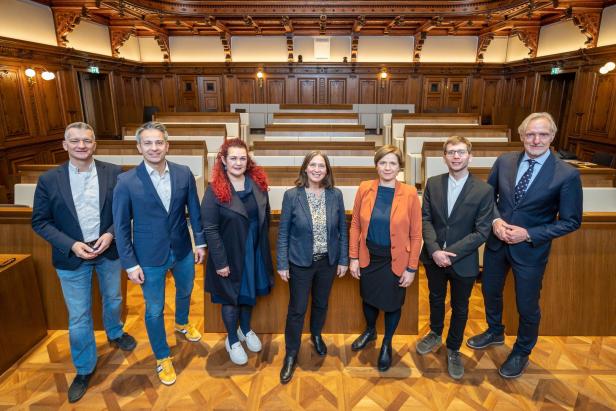 Eine Gruppe von sieben Personen posiert in einem holzgetäfelten Raum.