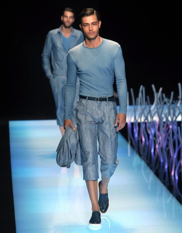 Ein Mann in blauer Kleidung läuft auf einem Laufsteg.