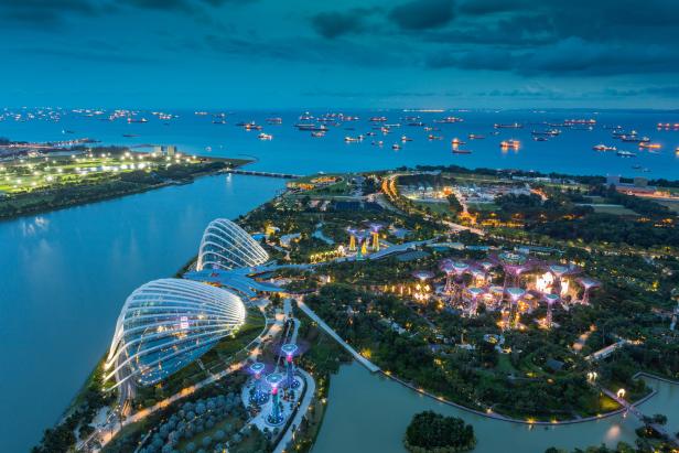 Luftaufnahme der beleuchteten Gardens by the Bay in Singapur bei Dämmerung.