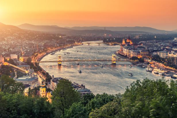 Blick auf Budapest mit der Kettenbrücke und dem ungarischen Parlament im goldenen Abendlicht.