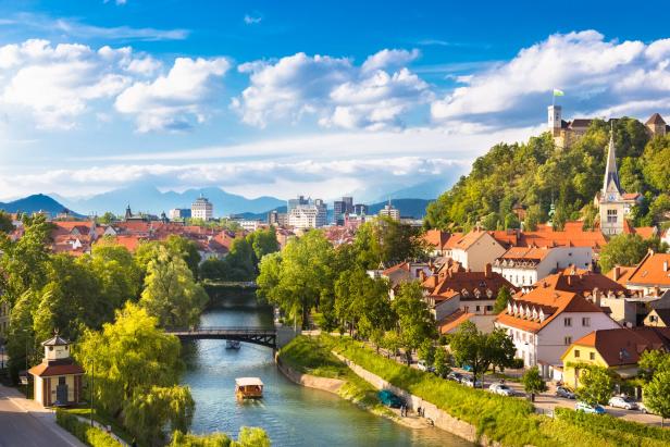 Blick auf Ljubljana mit dem Fluss Ljubljanica und der Burg im Hintergrund.