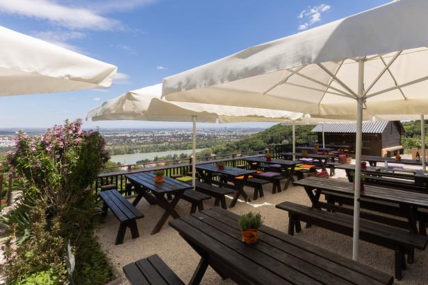 Ein Biergarten mit Tischen und Bänken bietet einen weiten Blick über die Stadt.