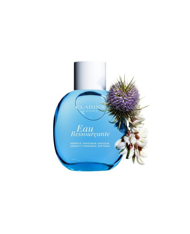 Eine Flasche „Eau Ressourçante“ von Clarins mit lila und weißen Blüten.