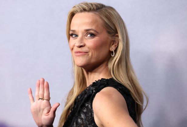Reese Witherspoon winkt in einem schwarzen Kleid.