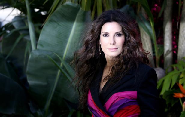 Sandra Bullock posiert vor tropischen Pflanzen.