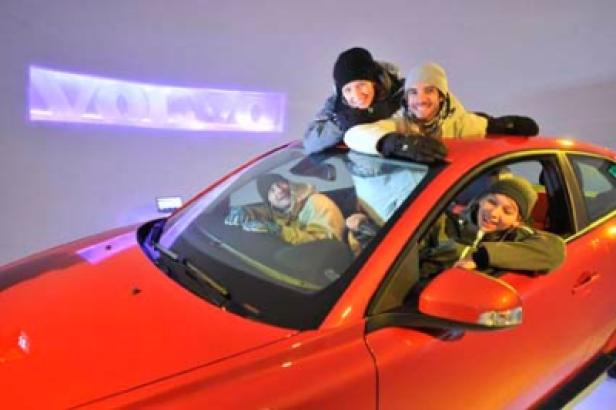 Vier Personen posieren auf und in einem roten Auto.