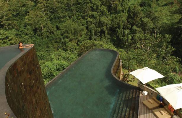 Eine Frau entspannt in einem Infinity-Pool mit Blick auf einen üppigen, grünen Dschungel.
