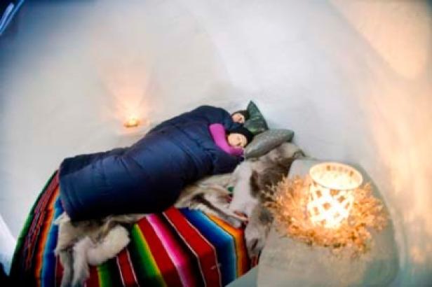 Zwei Personen schlafen in Schlafsäcken in einem Iglu.