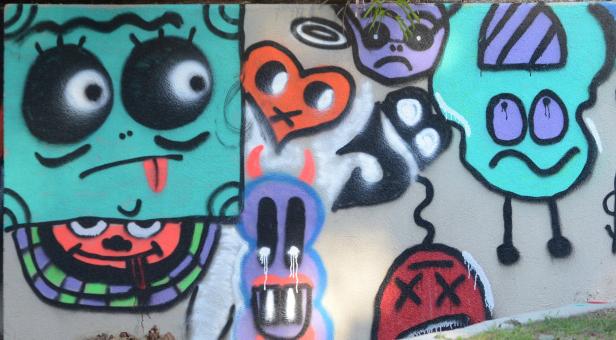 Eine Wand mit Graffiti-Kunst, die verschiedene Cartoon-Gesichter und Formen zeigt.
