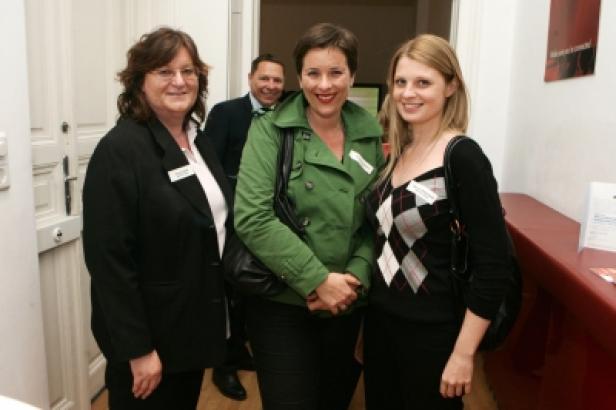 Drei Frauen posieren für ein Foto, eine weitere Person steht im Hintergrund.