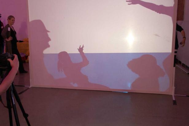 Schattenrisse von Personen werden auf eine Leinwand projiziert.