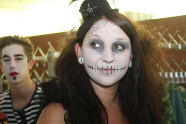 Eine Frau mit gruseliger Halloween-Schminke und einem kleinen Hut.