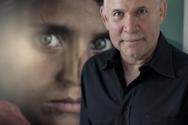 Steve McCurry vor einem Porträt des „Afghan Girl“.