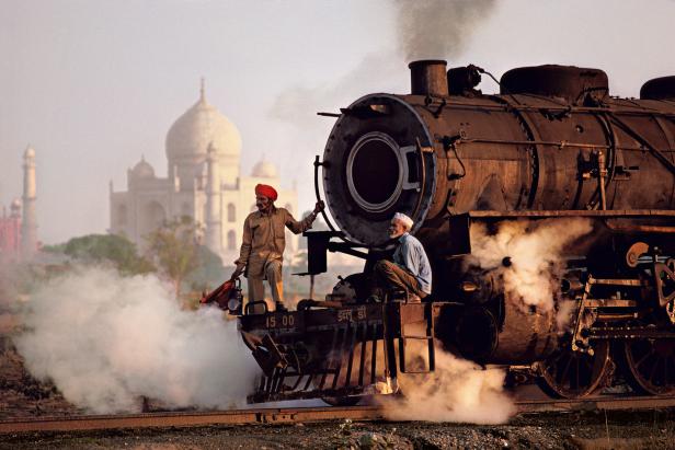Zwei Männer auf einer Dampflokomotive vor dem Taj Mahal.