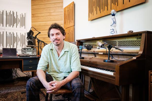 Ein Mann sitzt vor einem Klavier in einem Musikstudio.