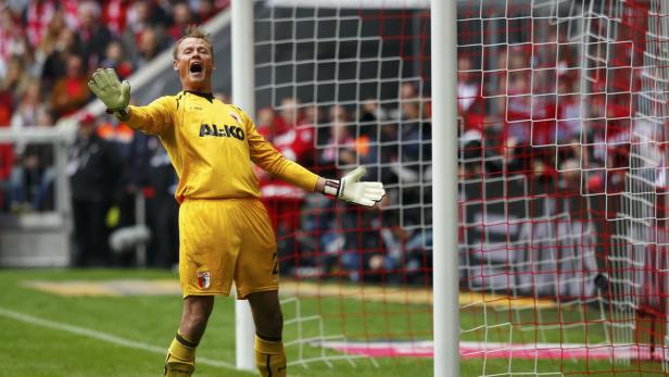 Ein Torwart in gelber Uniform jubelt vor dem Tor.