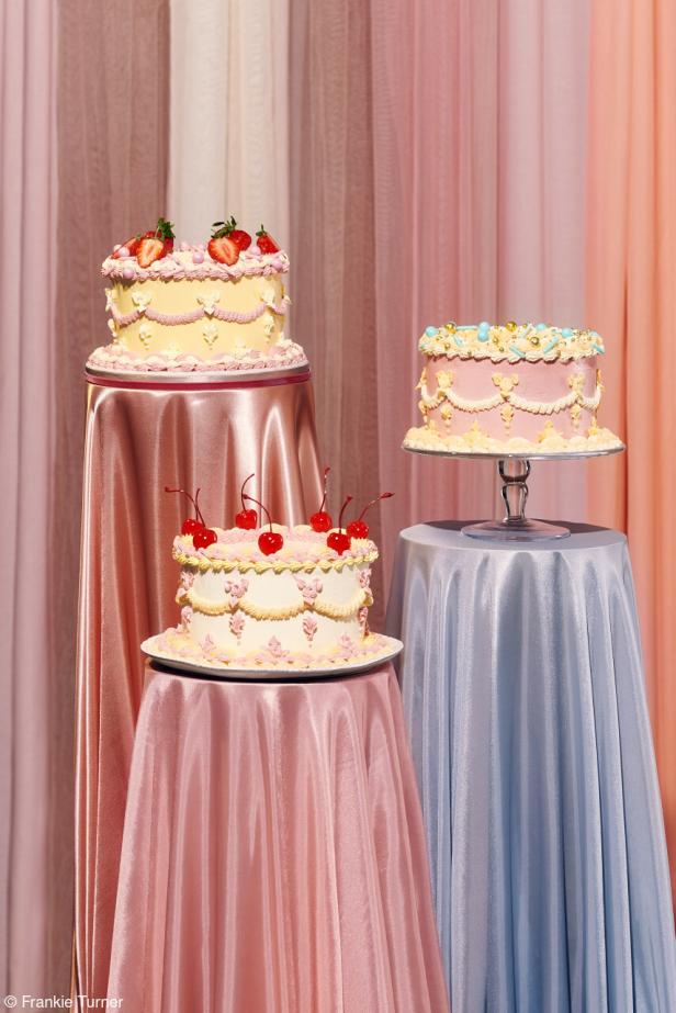 Drei verzierte Kuchen stehen auf Tischen mit pastellfarbenen Tischdecken.