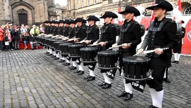 Eine Gruppe von Trommlern in historischen Kostümen tritt auf einer Straße auf.