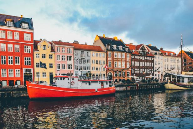 Ein rotes Boot liegt vor den bunten Häusern von Nyhavn in Kopenhagen vor Anker.