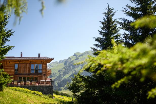 Ein Holzhaus mit Balkon vor einer Bergkulisse.