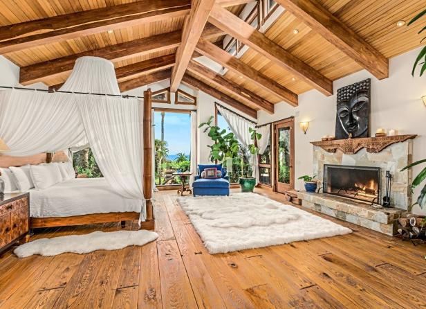 Ein Schlafzimmer mit Himmelbett, Kamin und Blick auf das Meer.