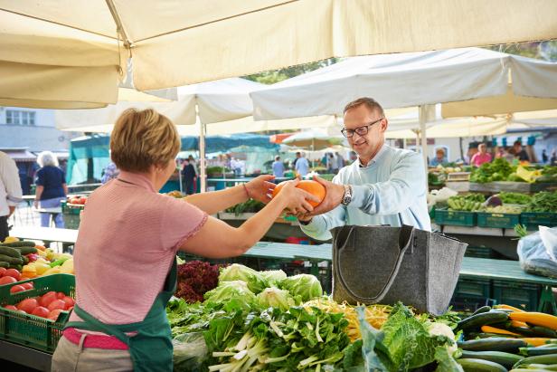 Ein Mann kauft auf einem Markt einen Kürbis.
