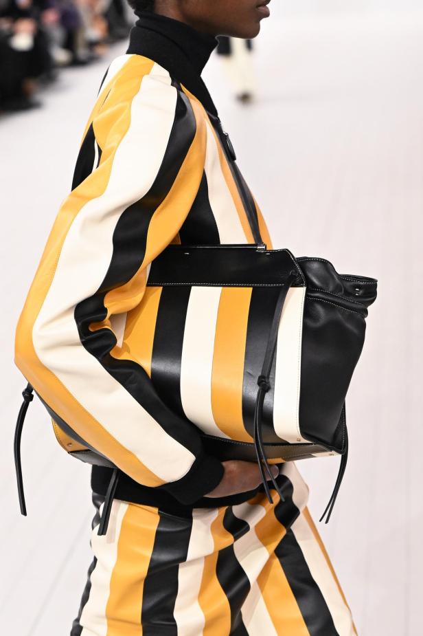 Eine Person trägt eine gestreifte Jacke und eine passende Handtasche.