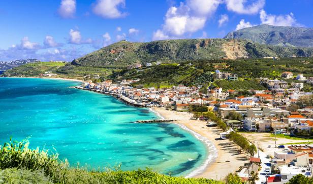 Ein Küstenort auf Kreta mit türkisfarbenem Wasser und roten Ziegeldächern.