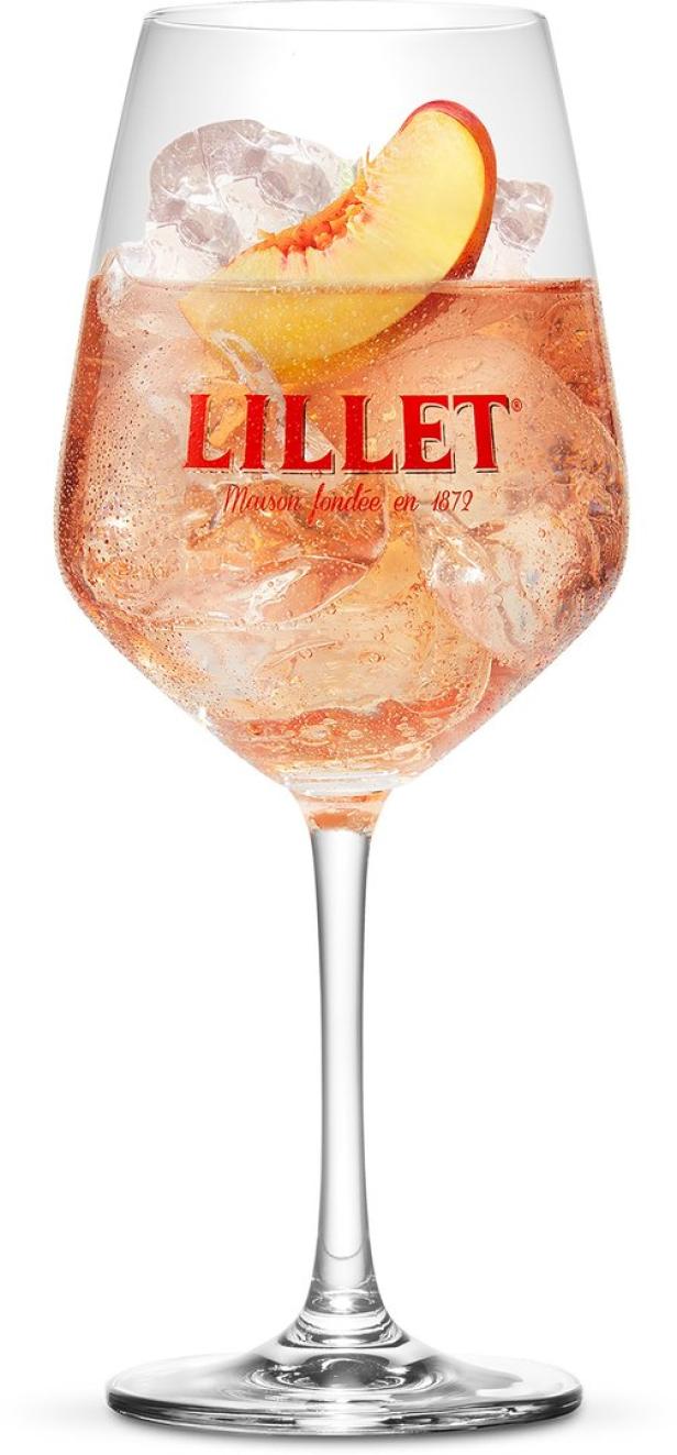 Ein Glas Lillet mit Eiswürfeln und einer Pfirsichspalte.