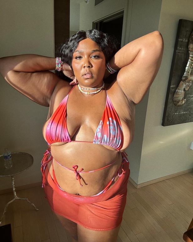 Lizzo posiert in einem rot-pinken Bikini und einem passenden Sarong.