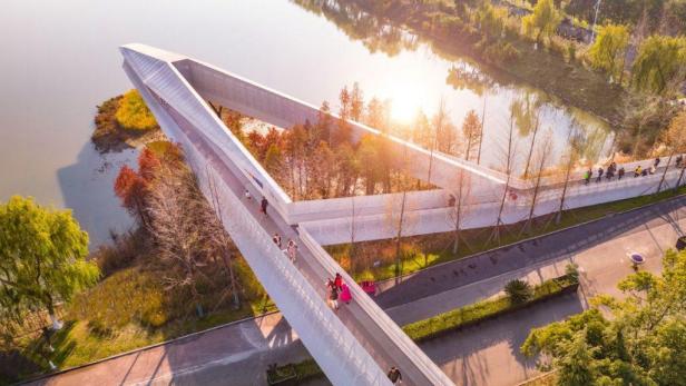 Luftaufnahme einer modernen Brücke im Fish Tail Park, auf der Menschen spazieren gehen.