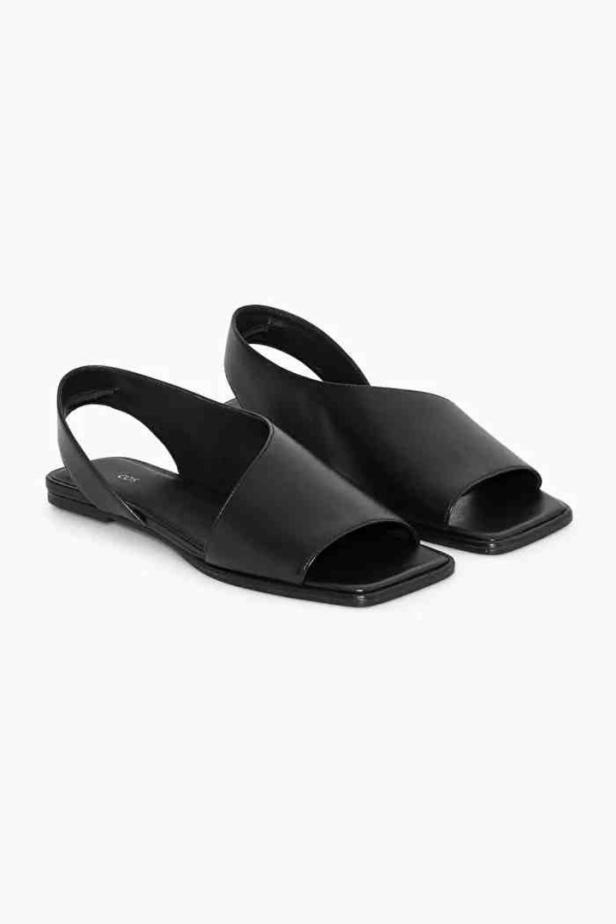 Ein Paar schwarze Ledersandalen mit eckiger Spitze stehen auf einem weißen Hintergrund.