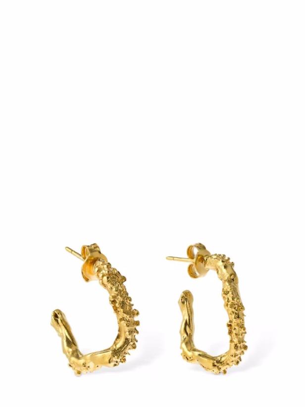 Nahaufnahme von zwei goldenen, unregelmäßig geformten Ohrringen.