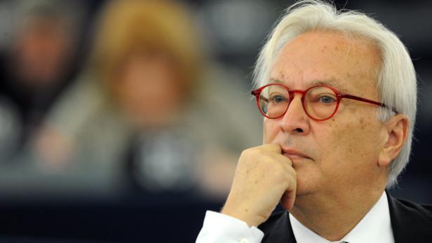 Ein Mann mit roten Brillengläsern und weißem Haar denkt nach.