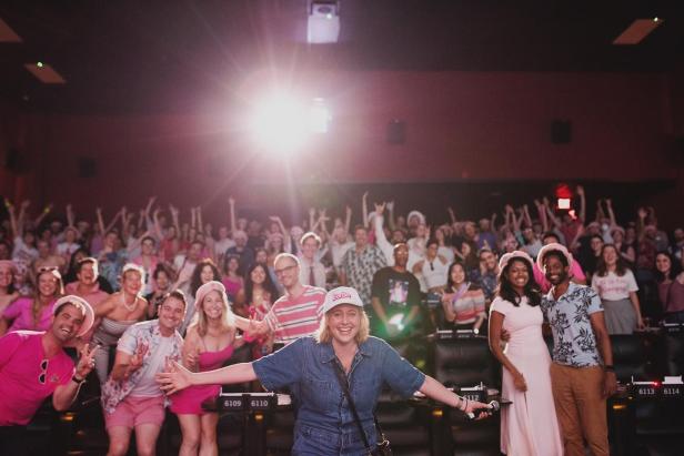 Greta Gerwig steht vor einem Kinopublikum, das in Pink gekleidet ist.