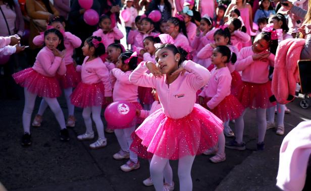 Eine Gruppe junger Mädchen in rosa Tutus tanzt auf der Straße.
