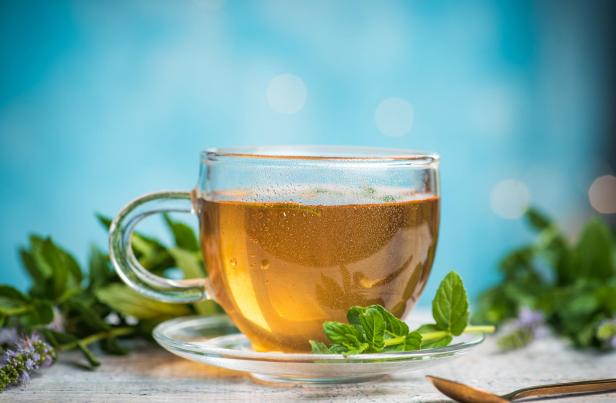 Mint tea in a glass teacup against blue background