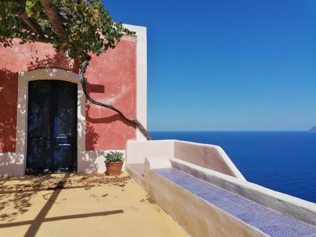 Ein Gebäude mit einer blauen Tür und Blick auf das Meer in Sizilien.