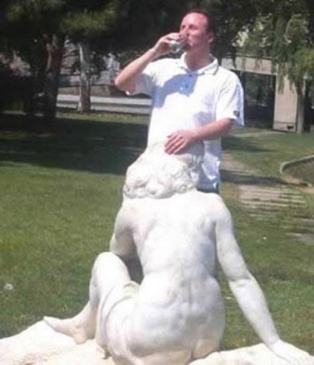 Ein Mann trinkt Wasser, während er eine weibliche Statue berührt.