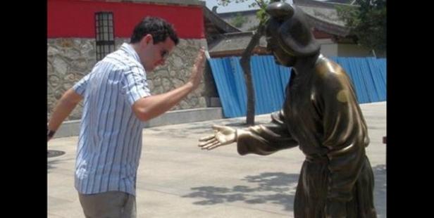 Ein Mann gibt einer Bronzestatue ein High-Five.