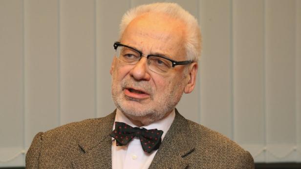 Ein älterer Mann mit Brille und Fliege in einem Tweed-Sakko.