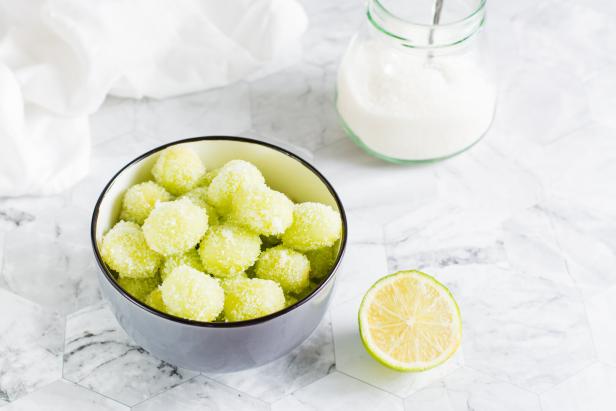 Eine Schüssel mit zuckerüberzogenen grünen Weintrauben und eine halbe Limette.
