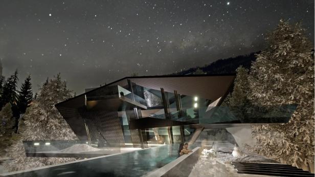 Ein modernes Haus mit Pool unter einem sternenklaren Nachthimmel.