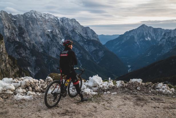 Ein Radfahrer der UAE-Mannschaft steht vor einer Berglandschaft.