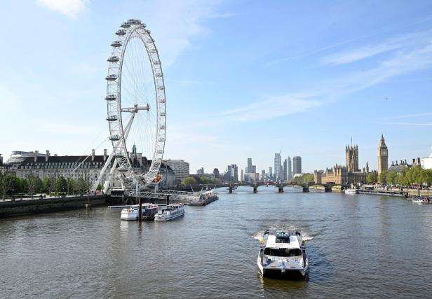 Der London Eye und der Big Ben, gesehen von der Themse mit einem Boot im Vordergrund.