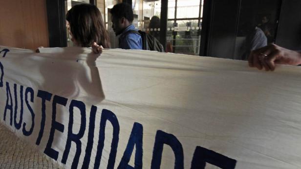 Menschen halten ein Banner mit der Aufschrift „Austeridade“.