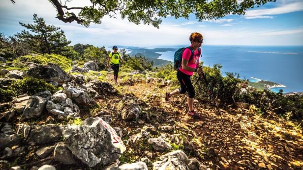 Wanderer auf einem felsigen Pfad mit Blick auf Cres und Lošinj in Kroatien.